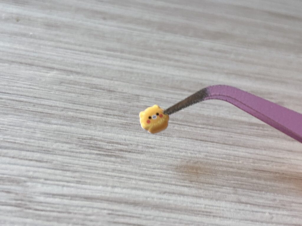 ピンセットでつまんだくま柄の小さいぷくぷくシール