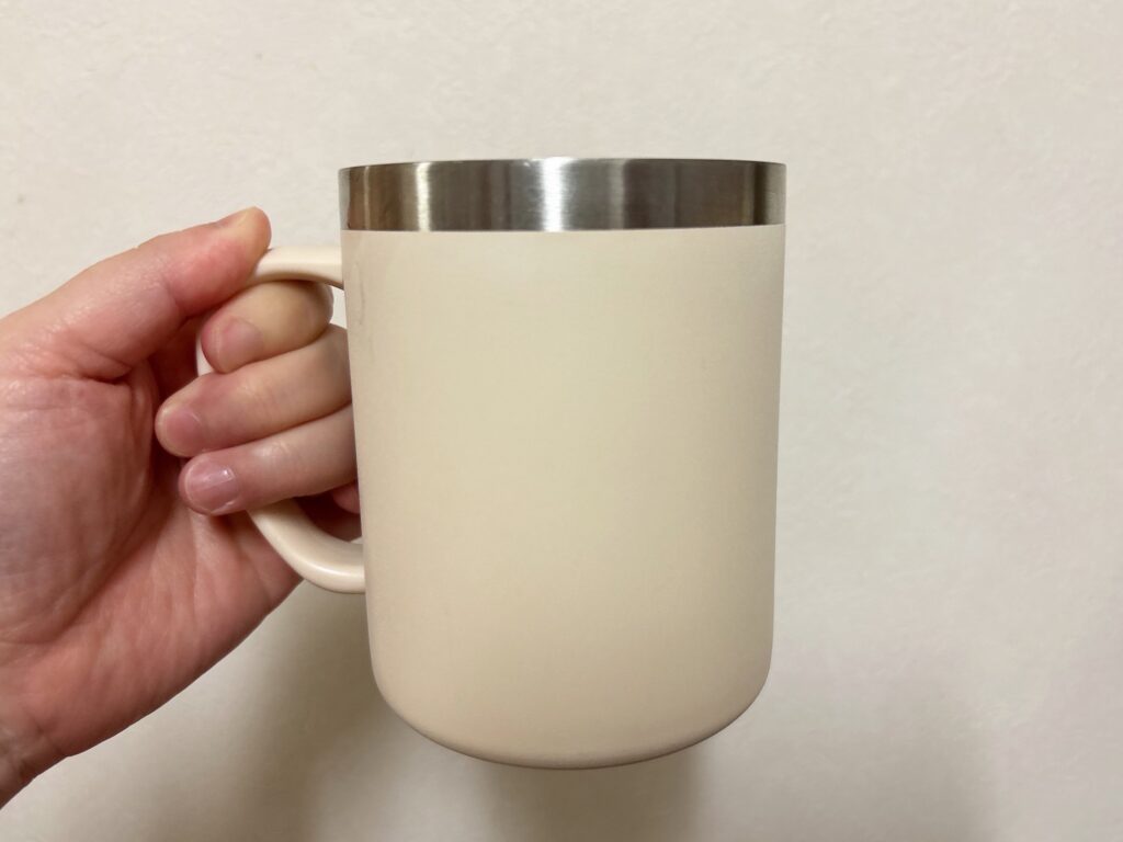 ダイソーの三層構造吸熱マグカップを手に持っているようす