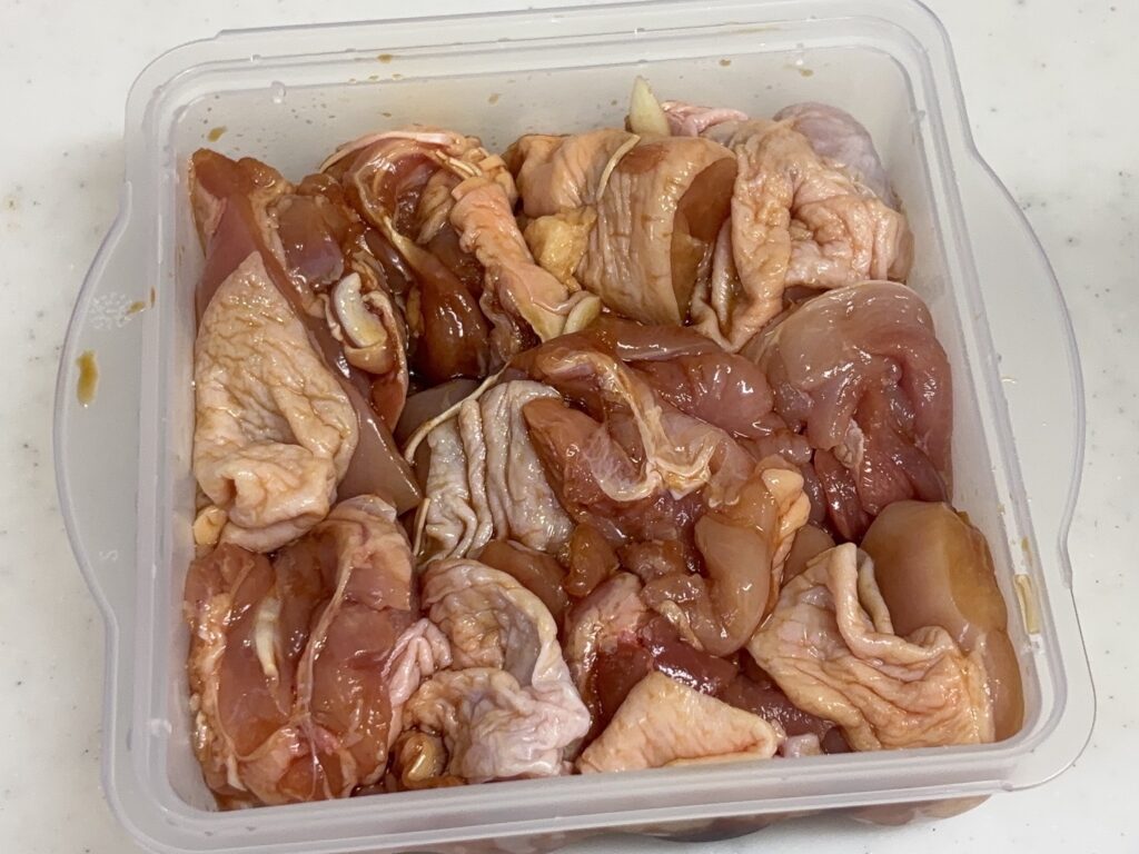 下味をつけた鶏肉をからあげ職人の容器の溝に沿って並べていれた画像