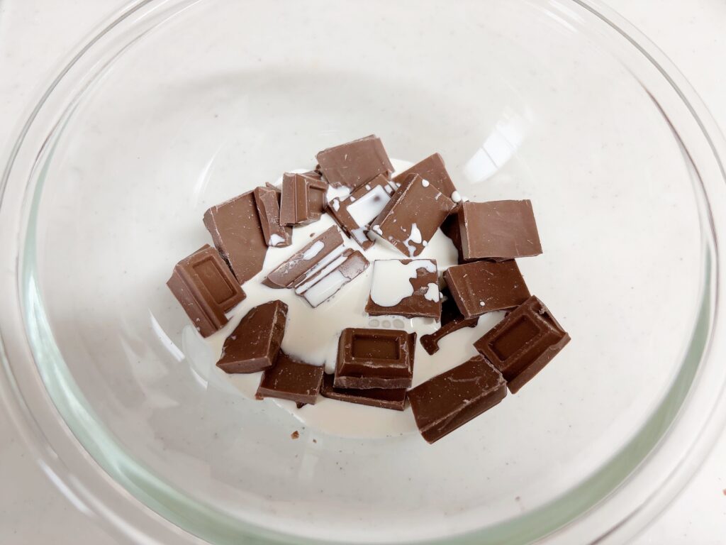 耐熱ボウルに割った板チョコと生クリームを入れている様子