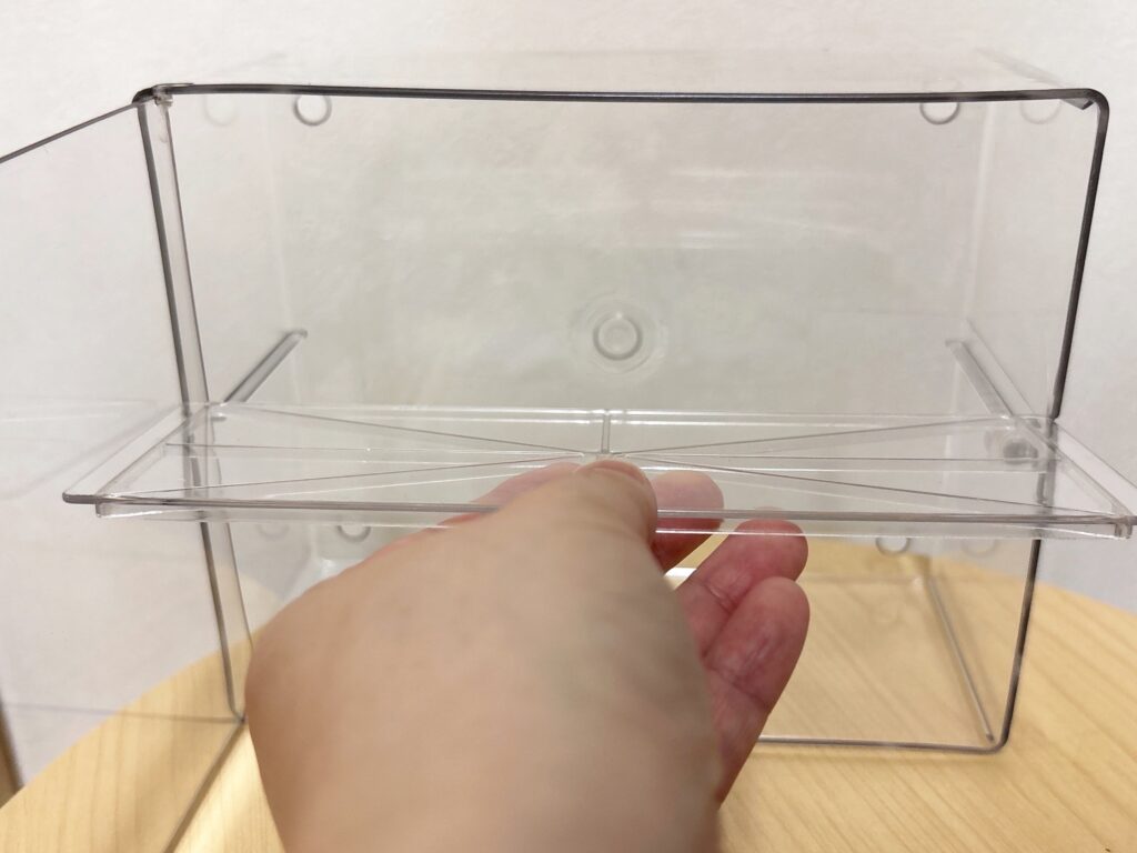 ダイソー壁に付けられる透明コレクションケースの仕切りを取り外している様子